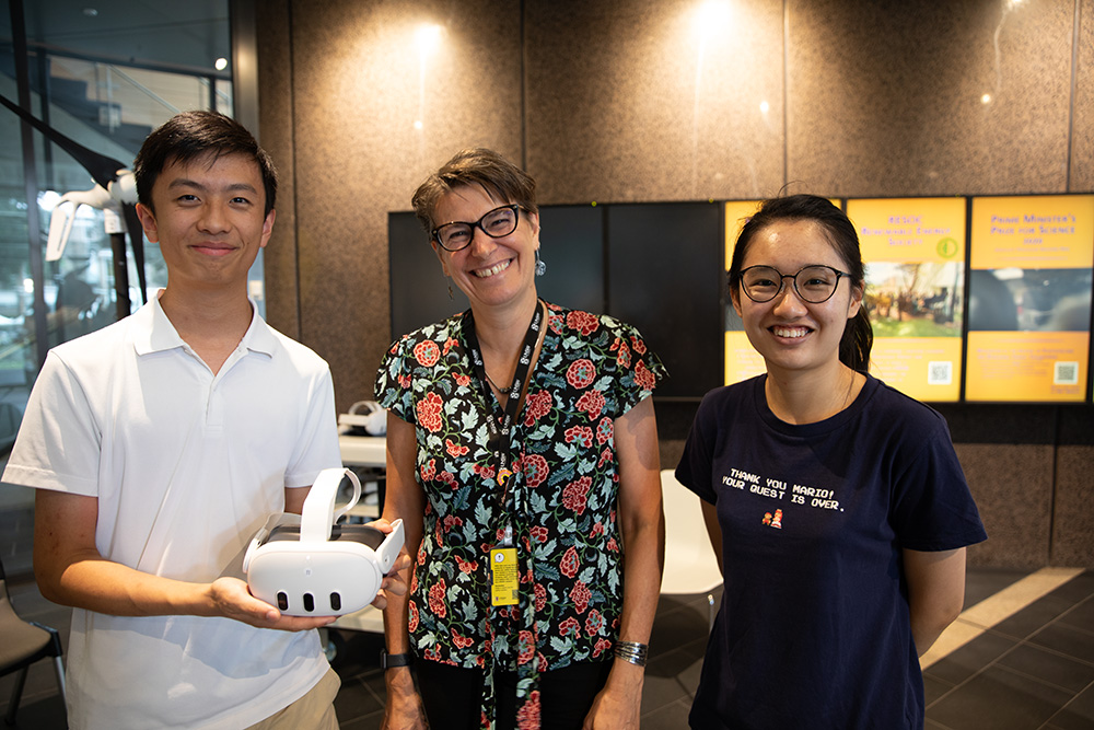 Three people standing holding a VR head set