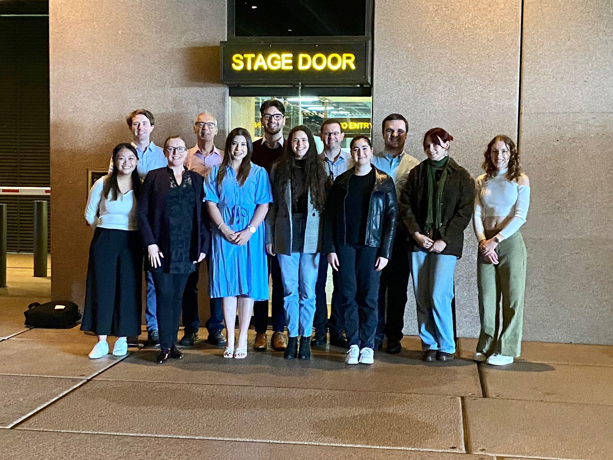 A group of people stand in front of stage door