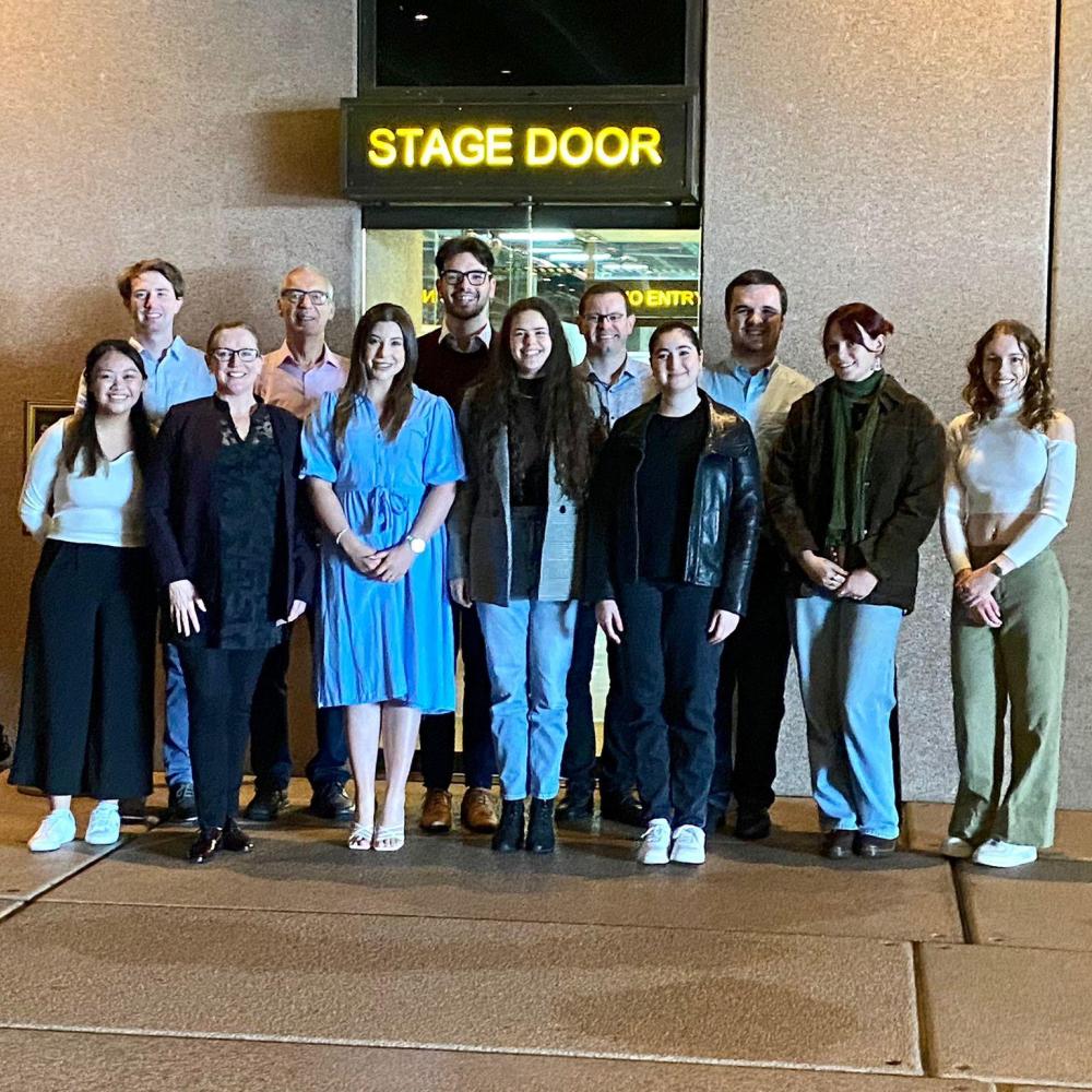 A group of people stand in front of stage door