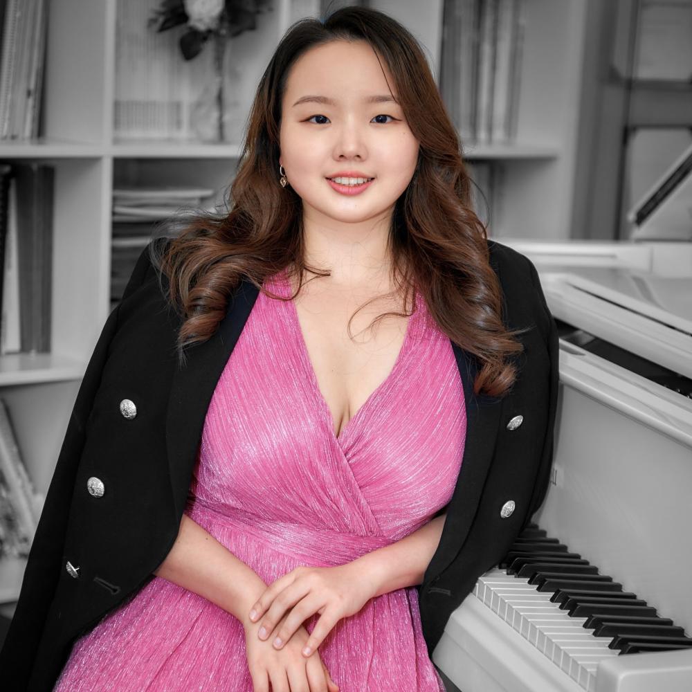 girl in pink dress sitting by the piano